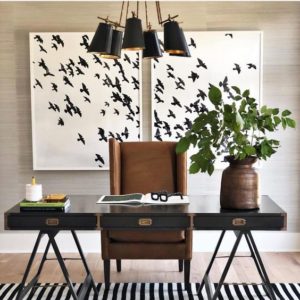 a home office with a leather desk chair and images of a flock of birds on the wall